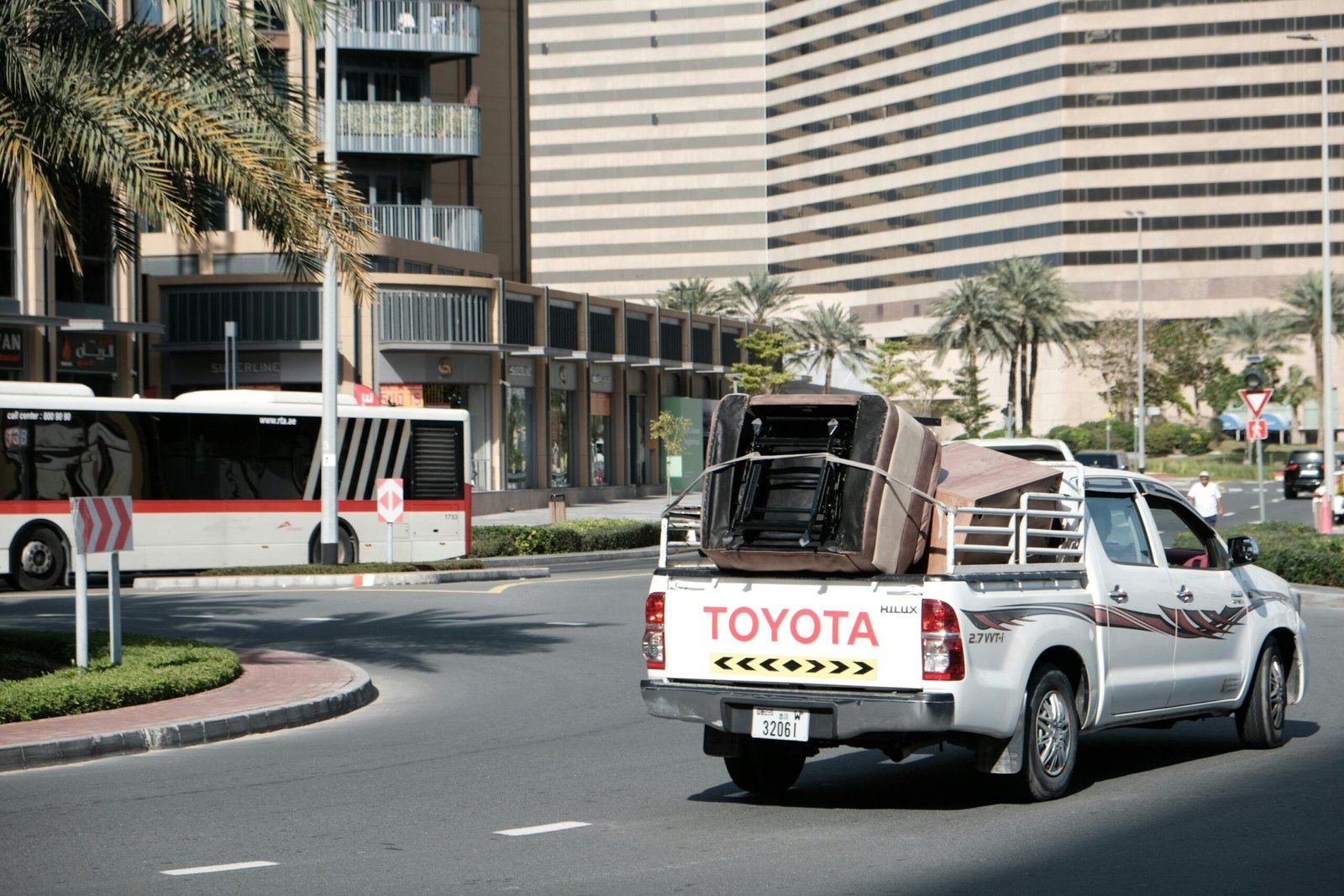 Busy street scene in downtown Dubai with a transport vehicle and bus amidst modern architecture.