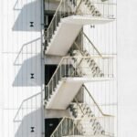 High stairway of contemporary stairway with metal railing of white wall of building in sunlight